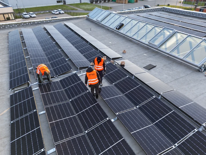 Solarmodule und drei Montagekräfte auf einem Gewerbeflachdach mit Lichtband